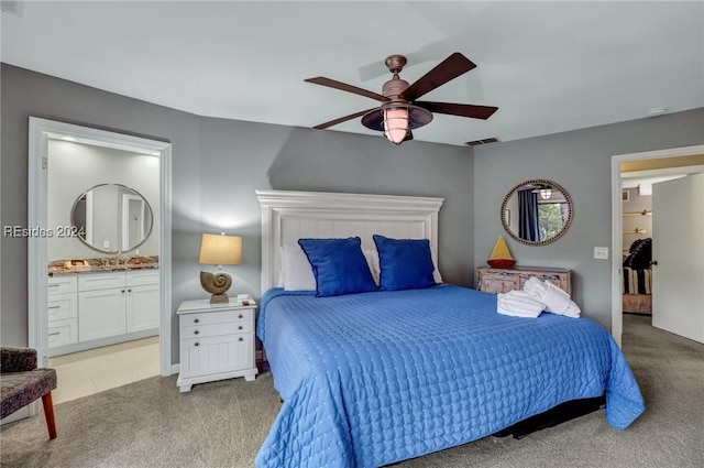 bedroom with light carpet, ceiling fan, and ensuite bath