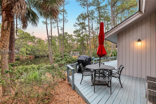 deck at dusk with a water view and grilling area