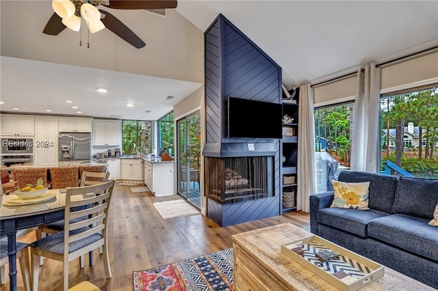 living room featuring ceiling fan, lofted ceiling, light wood-type flooring, and a wealth of natural light