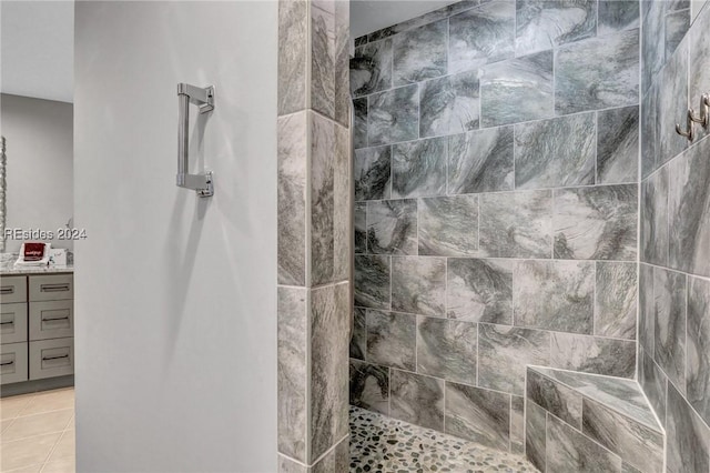 bathroom with a tile shower, vanity, and tile patterned flooring