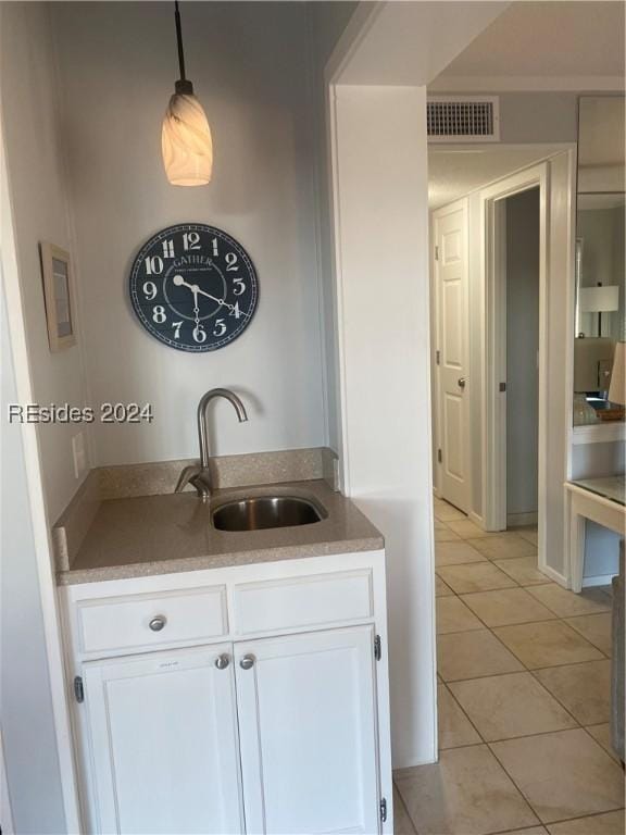 bar featuring light tile patterned floors, decorative light fixtures, sink, and white cabinets