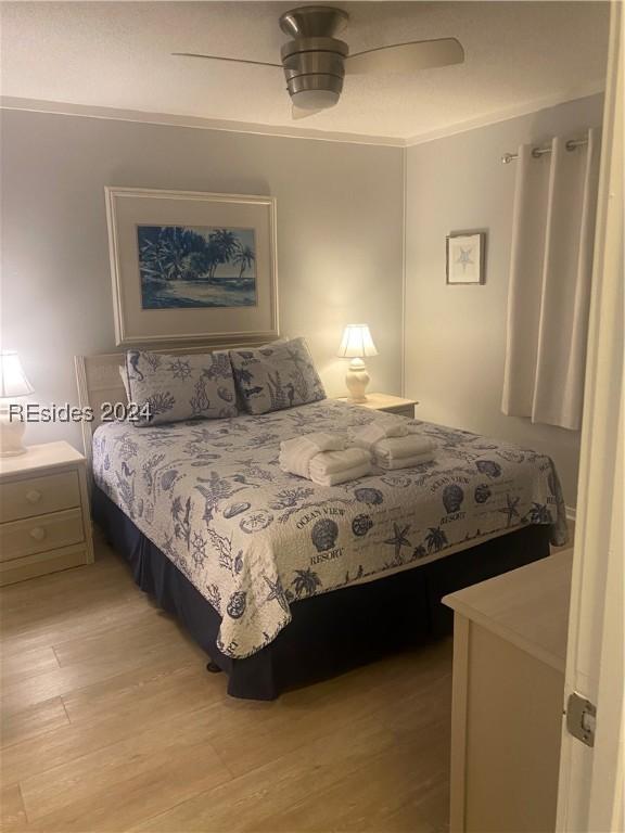 bedroom featuring ornamental molding, light wood-type flooring, and ceiling fan