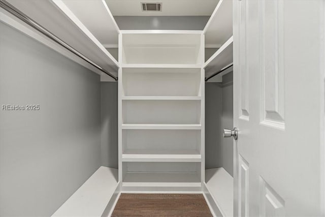 walk in closet with dark wood-type flooring