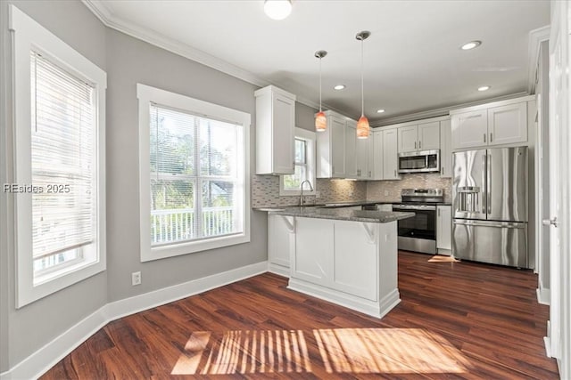 kitchen featuring decorative light fixtures, appliances with stainless steel finishes, a kitchen breakfast bar, kitchen peninsula, and white cabinets