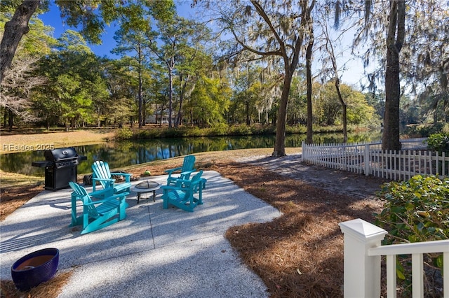 exterior space featuring grilling area, a water view, and an outdoor fire pit