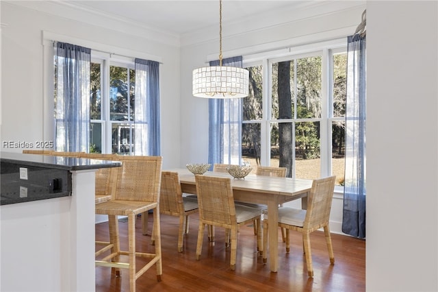 dining room with hardwood / wood-style floors, ornamental molding, a wealth of natural light, and a notable chandelier