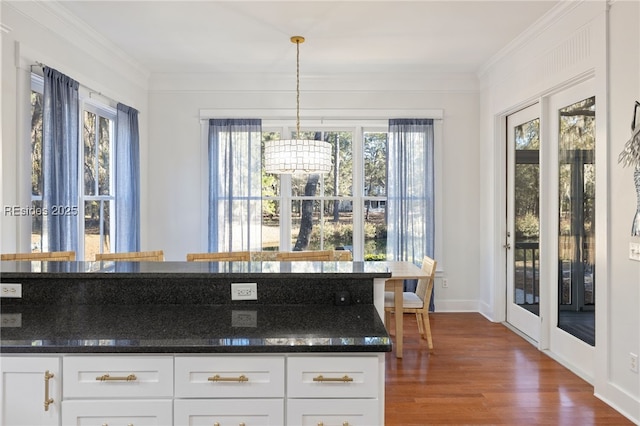 kitchen featuring pendant lighting, crown molding, dark hardwood / wood-style flooring, and white cabinets