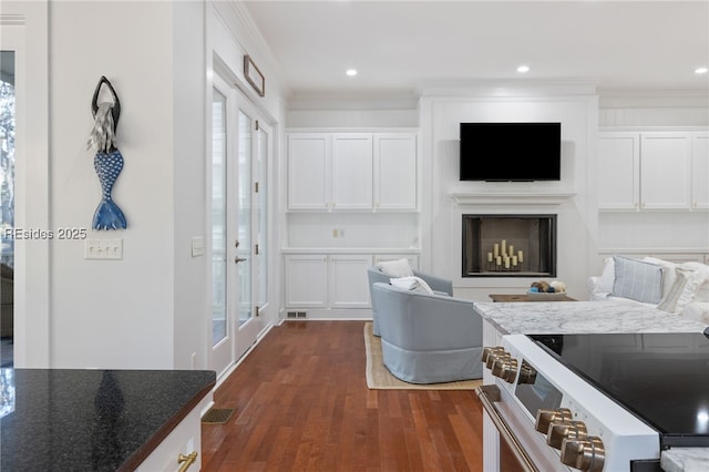 kitchen featuring electric stove, ornamental molding, white cabinets, dark hardwood / wood-style flooring, and dark stone counters