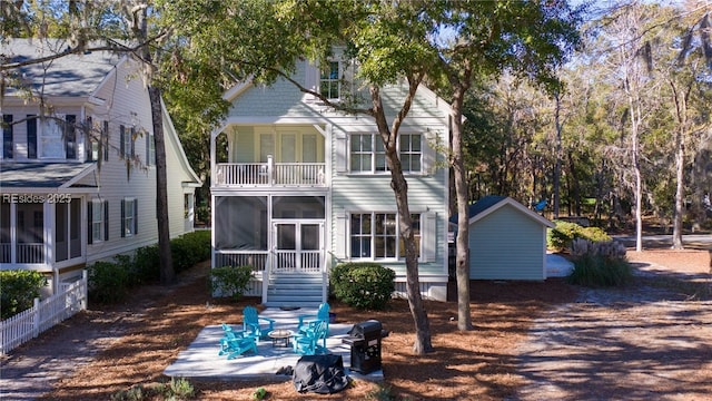 back of house with a balcony, a sunroom, and a patio