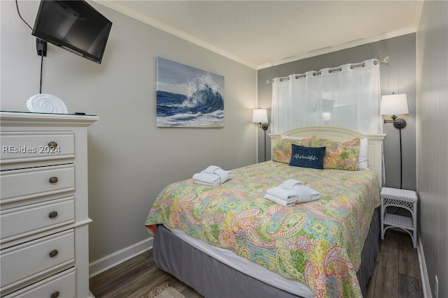 bedroom featuring crown molding and dark hardwood / wood-style floors