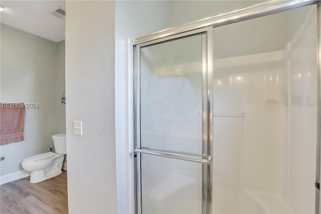 bathroom with hardwood / wood-style floors, toilet, and walk in shower