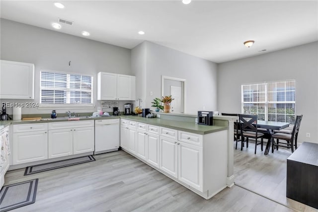 kitchen with sink, white cabinetry, light hardwood / wood-style flooring, white dishwasher, and kitchen peninsula