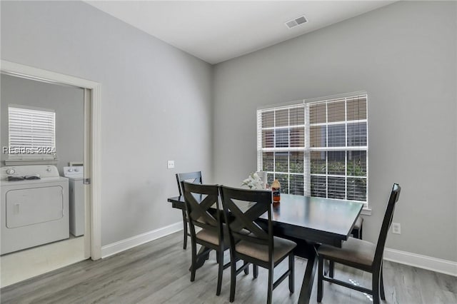 dining space with wood-type flooring and separate washer and dryer