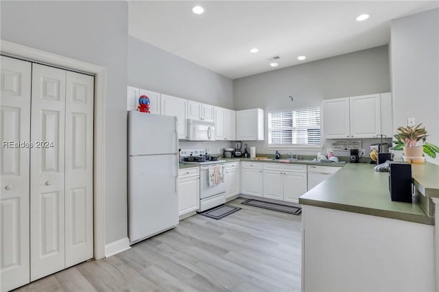 kitchen with sink, light wood-type flooring, white cabinets, white appliances, and a high ceiling