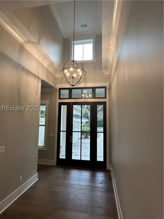 foyer entrance featuring dark hardwood / wood-style flooring, a notable chandelier, a towering ceiling, and crown molding