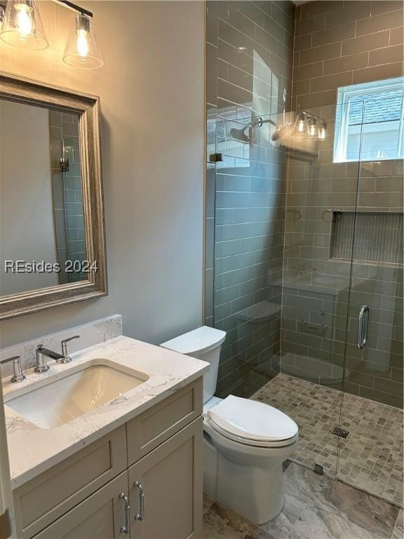 bathroom with a shower with door, vanity, and toilet