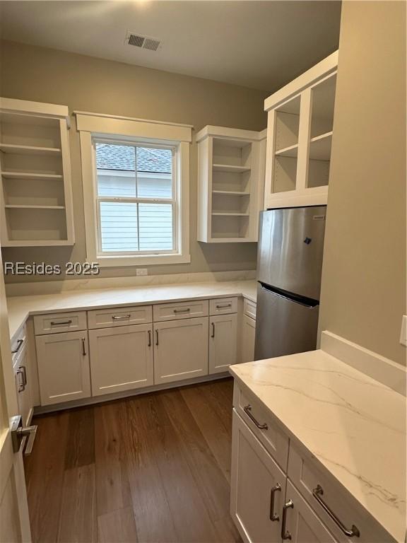 kitchen with stainless steel refrigerator, dark hardwood / wood-style floors, light stone countertops, and white cabinets