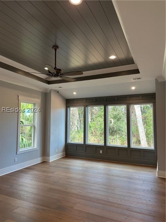 empty room featuring ceiling fan, light hardwood / wood-style floors, a raised ceiling, and wooden ceiling