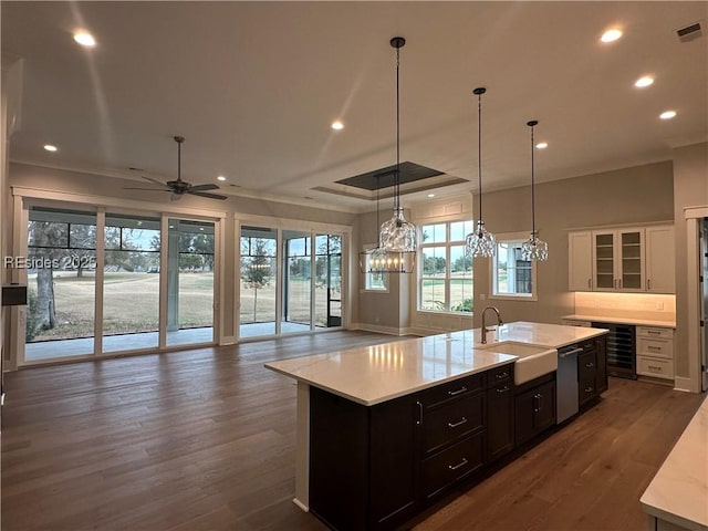 kitchen with sink, white cabinetry, hanging light fixtures, dishwasher, and an island with sink