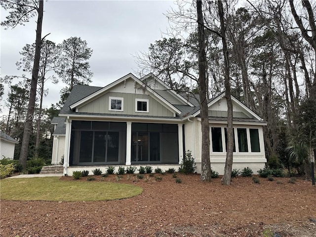 rear view of house featuring a yard and a sunroom