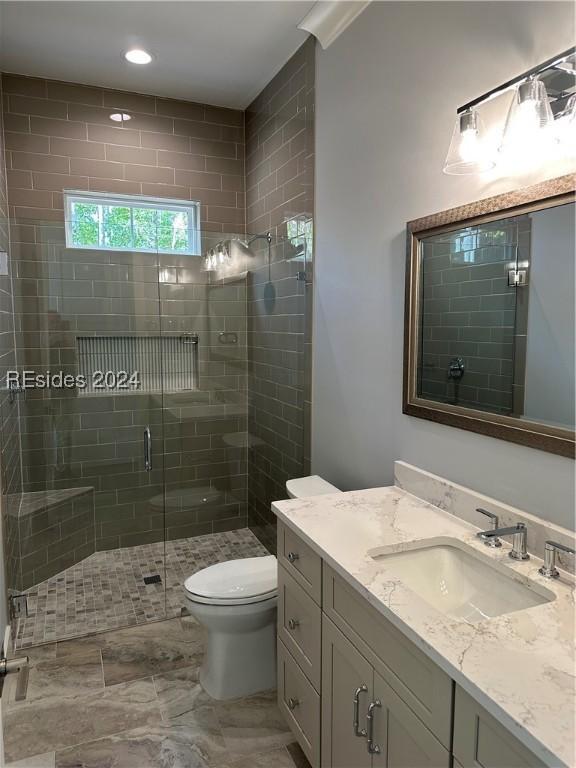 bathroom featuring vanity, toilet, and a shower with shower door