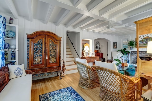 foyer entrance with beamed ceiling, ceiling fan, wood walls, and hardwood / wood-style flooring