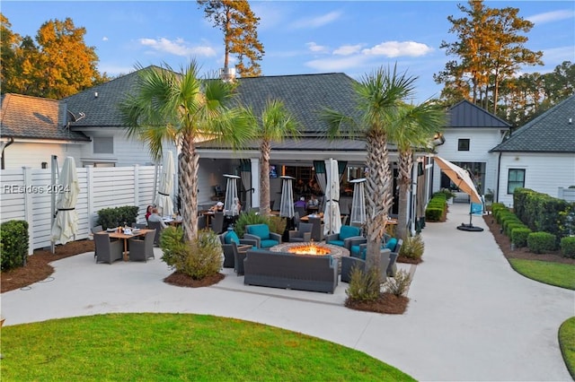 back of house with an outdoor living space with a fire pit and a patio area