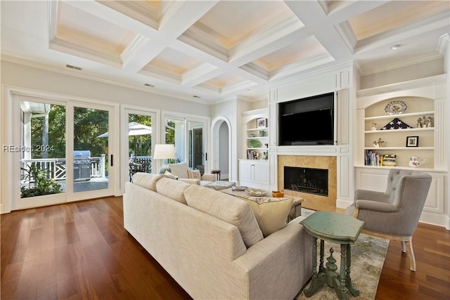 living room featuring built in shelves, dark wood-type flooring, ornamental molding, and beamed ceiling