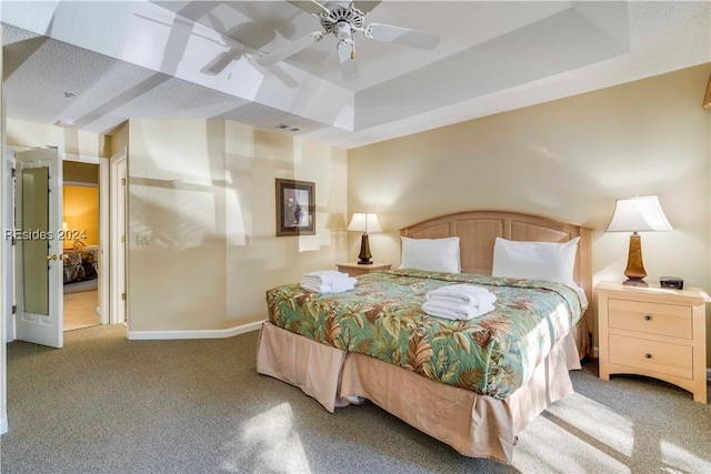 carpeted bedroom with ceiling fan and a tray ceiling