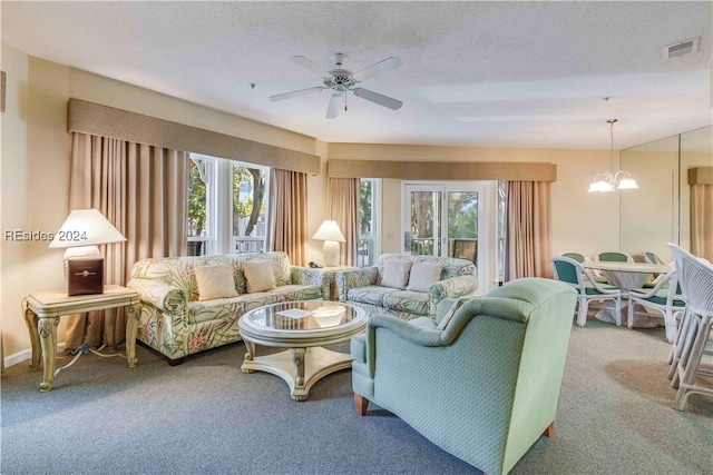 living room with carpet, ceiling fan with notable chandelier, and a textured ceiling