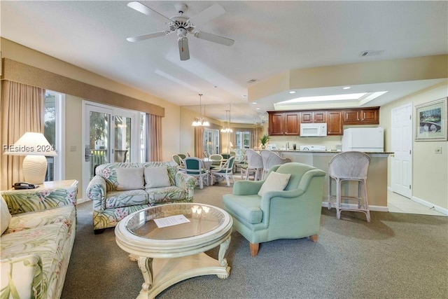 carpeted living room with ceiling fan with notable chandelier