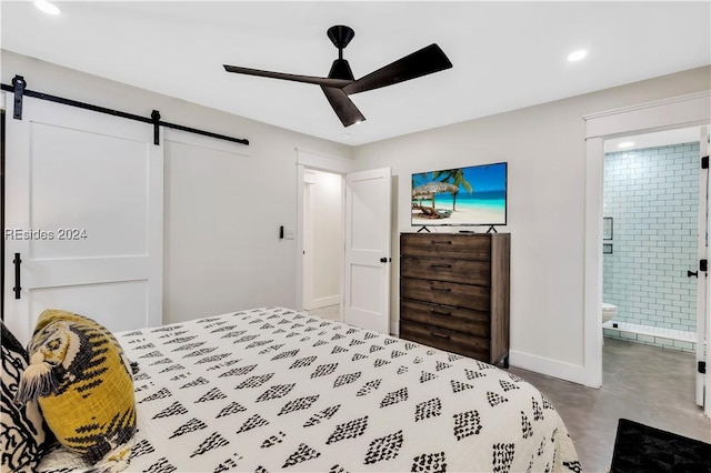 bedroom featuring ceiling fan, ensuite bathroom, a barn door, and concrete floors