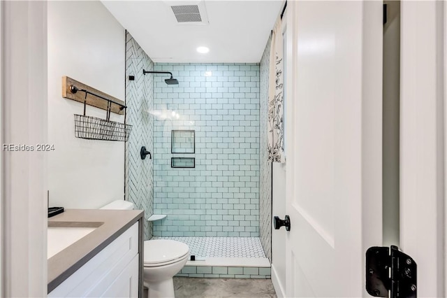 bathroom with vanity, toilet, and tiled shower