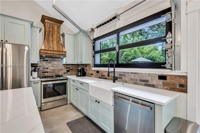 kitchen featuring premium range hood, appliances with stainless steel finishes, lofted ceiling, backsplash, and light stone counters