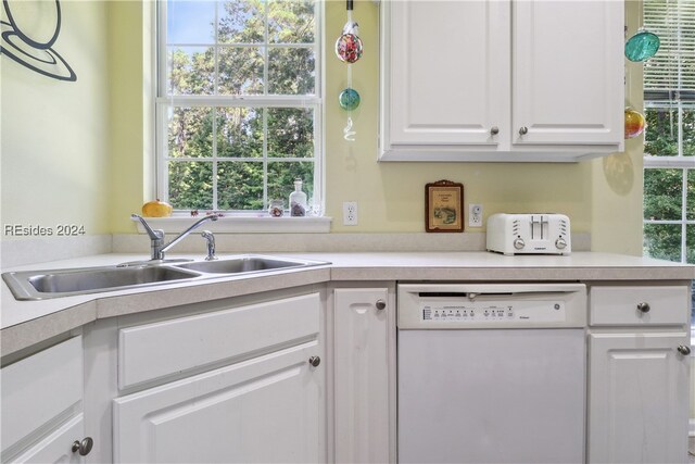 kitchen with white cabinetry, white dishwasher, and sink