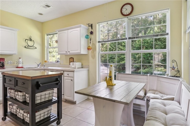 kitchen featuring white cabinetry, a kitchen island, sink, and light tile patterned floors