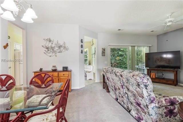 carpeted living room with ceiling fan with notable chandelier and a textured ceiling