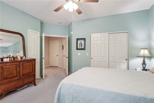 carpeted bedroom with a textured ceiling, a closet, and ceiling fan