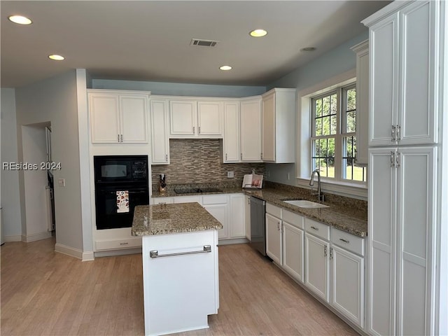 kitchen featuring sink, white cabinetry, dark stone countertops, a kitchen island, and black appliances