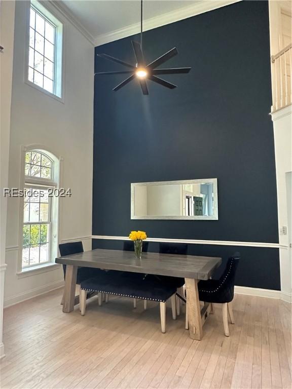 dining space featuring a high ceiling, crown molding, and light hardwood / wood-style flooring