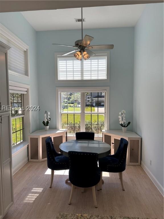 dining space with ceiling fan, a high ceiling, light hardwood / wood-style flooring, and a wealth of natural light