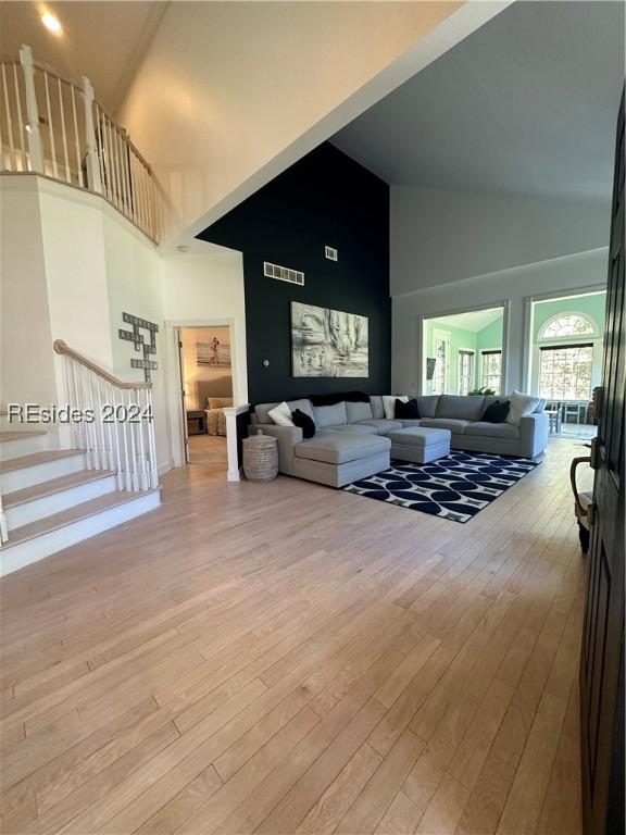 living room featuring high vaulted ceiling and light wood-type flooring