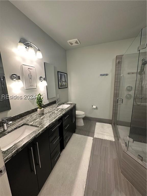 bathroom with an enclosed shower, vanity, and toilet