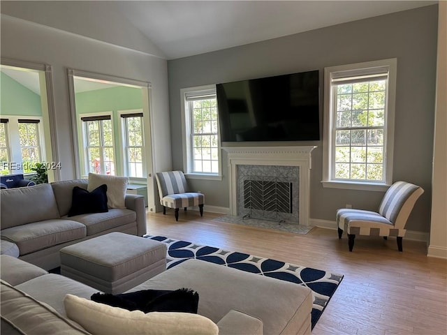 living room with lofted ceiling, a high end fireplace, and light wood-type flooring