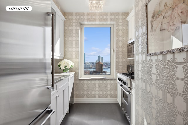 kitchen featuring a chandelier, dark tile patterned floors, white cabinets, and stainless steel appliances