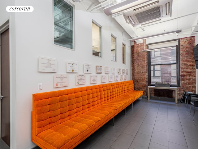 interior space with brick wall and dark tile patterned floors