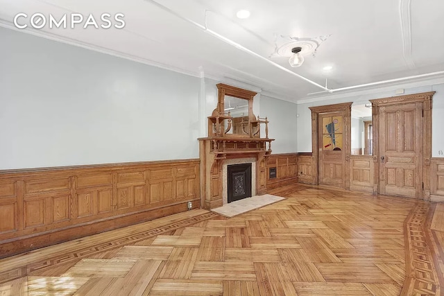 living room featuring crown molding, a fireplace, and light parquet floors