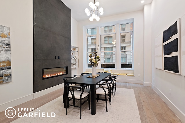 dining space featuring a fireplace, a chandelier, and light hardwood / wood-style flooring