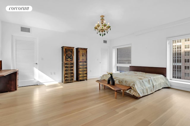 bedroom with a chandelier and light wood-type flooring