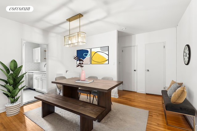 dining room with sink, a notable chandelier, and light hardwood / wood-style flooring